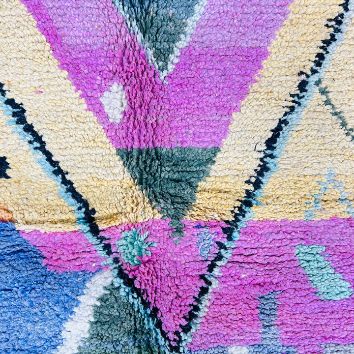 Colorful Moroccan wool rug with central pink diamond pattern and multicolored zigzags, handmade by Berber artisans.