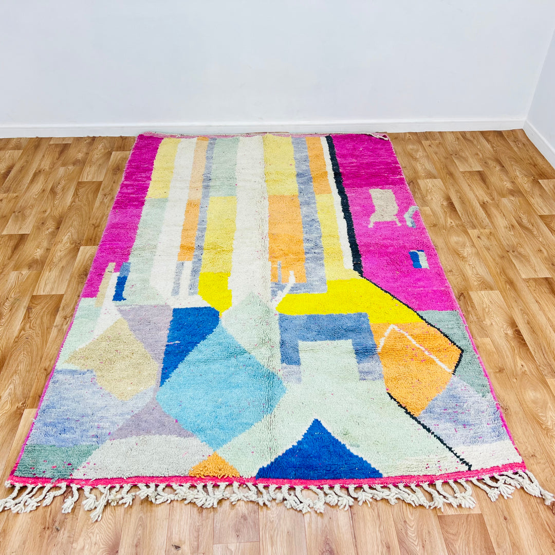 Modern Abstract Moroccan Wool Rug with vibrant colors and geometric patterns on wooden floor.