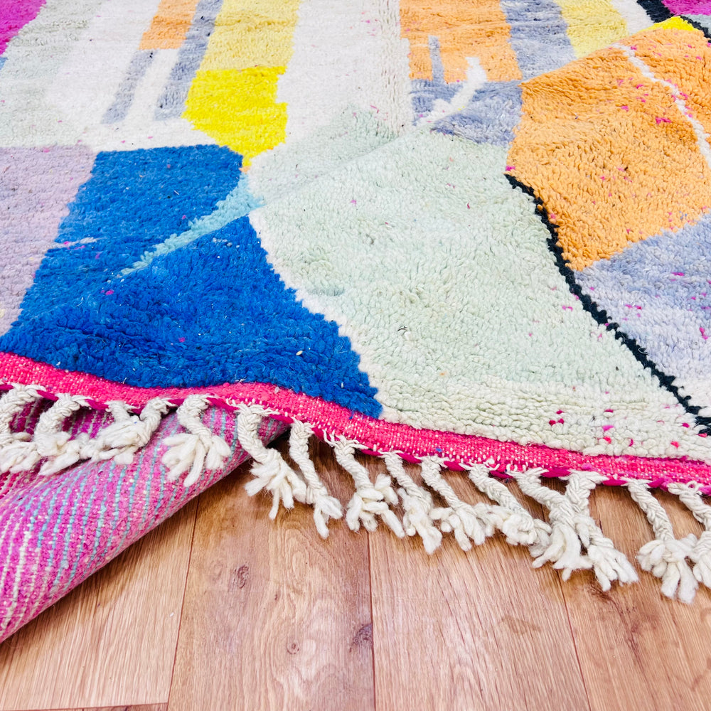 Colorful Modern Abstract Moroccan Wool Rug with geometric patterns and fringed edges on wooden floor.