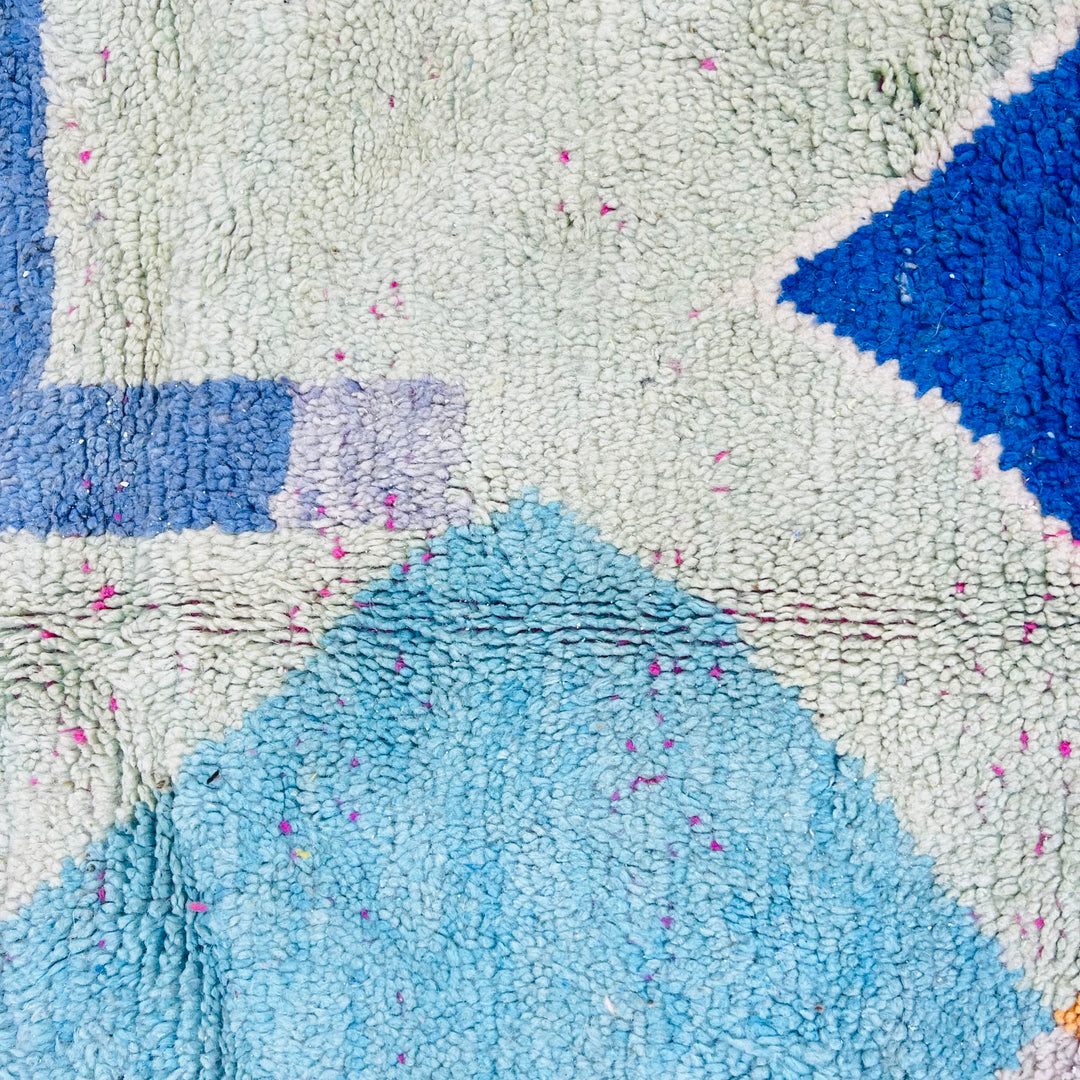 Close-up of Modern Abstract Moroccan Wool Rug with blue, pink, and cream geometric patterns showcasing vibrant colors and texture.