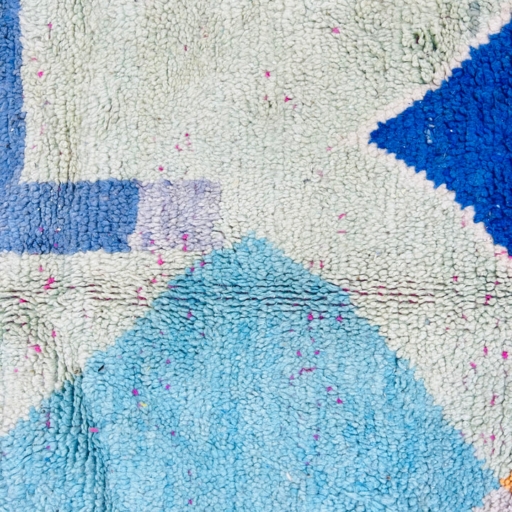 Close-up of Modern Abstract Moroccan Wool Rug with blue, pink, and cream geometric patterns showcasing vibrant colors and texture.