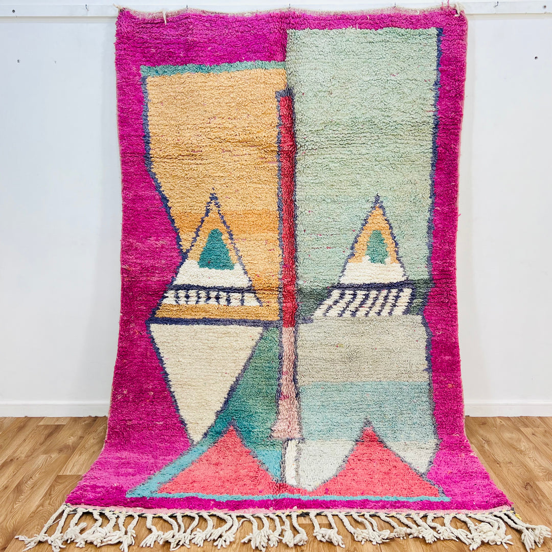 Geometric Moroccan wool rug with pyramid design in peach, mint, navy on fuchsia border. Traditional Berber handwoven style.
