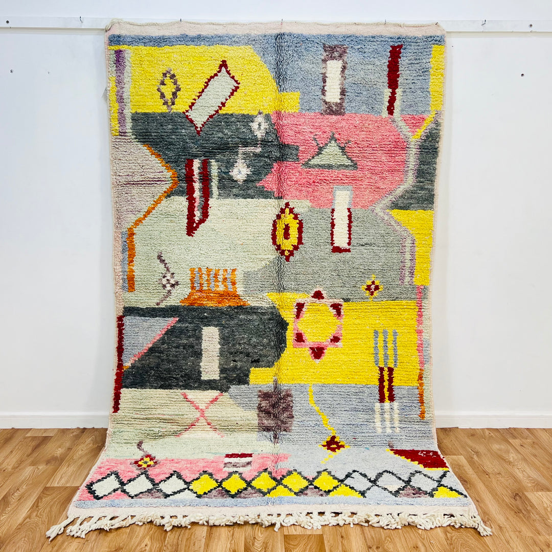 Abstract Berber Moroccan wool rug with geometric and symbolic shapes in yellow, black, grey, coral pink, and red. Handwoven by artisans.