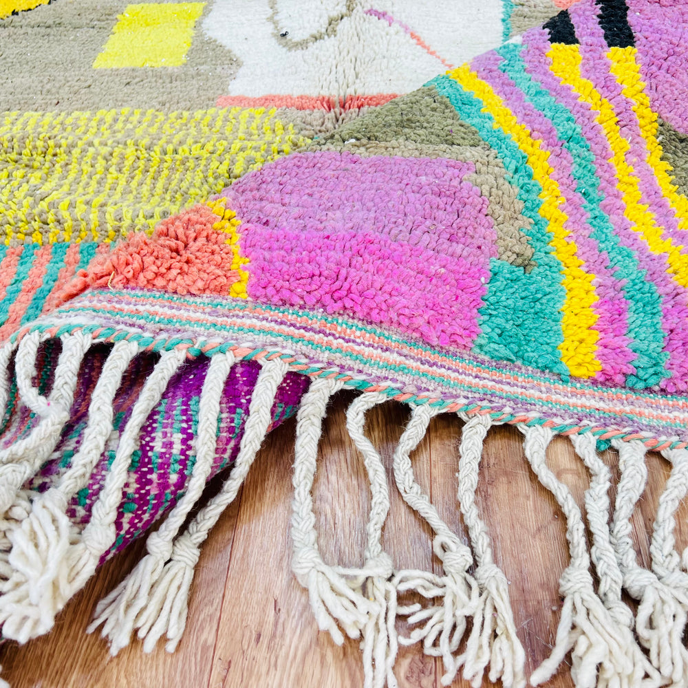 Colorful patchwork Moroccan wool rug with geometric and abstract designs in pink, yellow, turquoise. Handwoven Berber traditional craftsmanship.