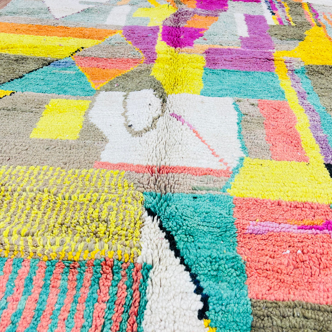 Vibrant patchwork Moroccan wool rug with geometric patterns in yellow, pink, turquoise, and earthy tones, 259x150 cm.