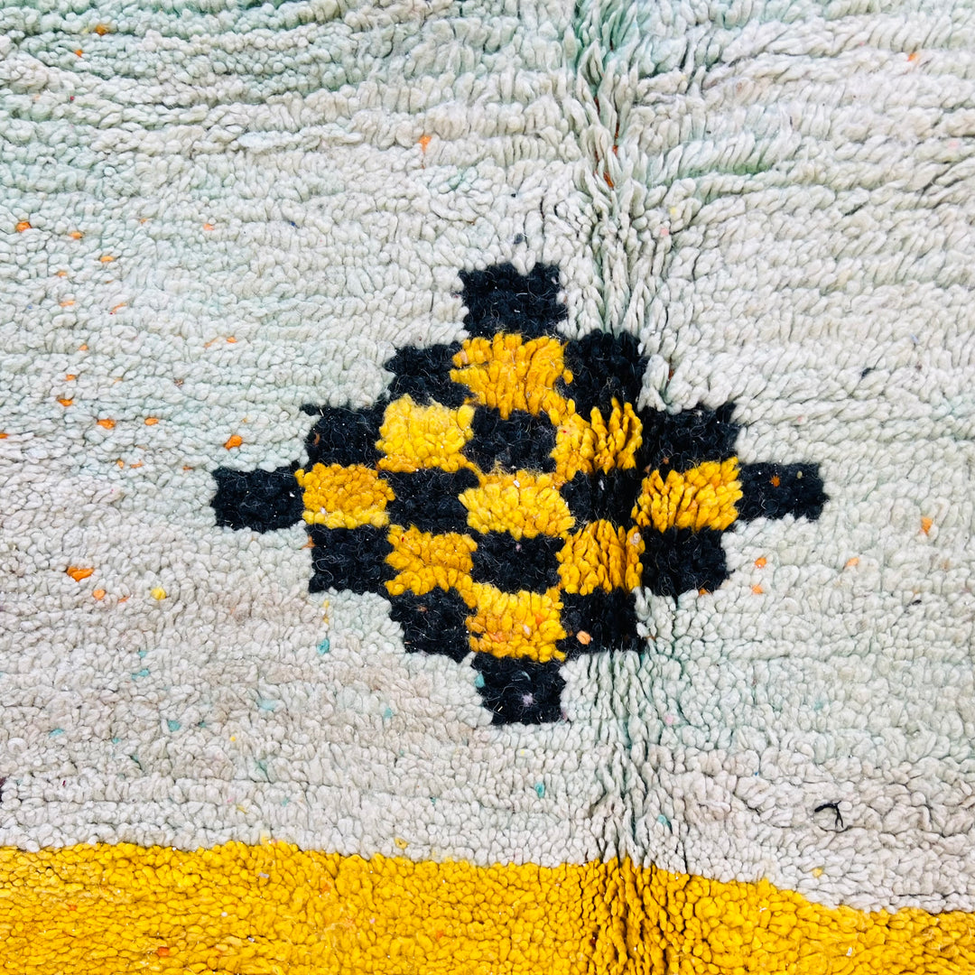Close-up of Playful Berber Moroccan wool rug featuring checkered yellow and black diamond design on a green and yellow background.