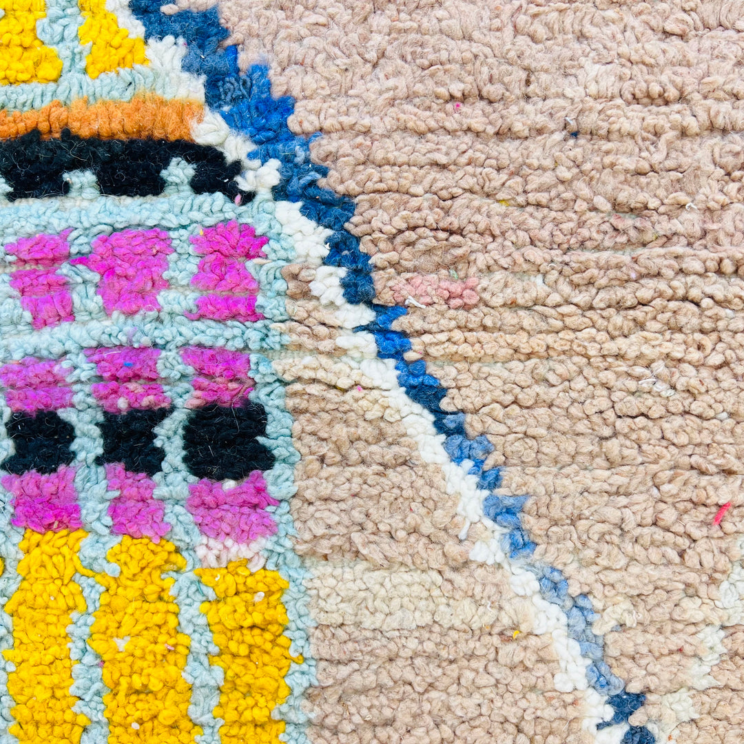 Brightly colored Moroccan wool rug close-up with pink, yellow, blue patterns - handmade Berber design from Morocco. 245x145 cm.