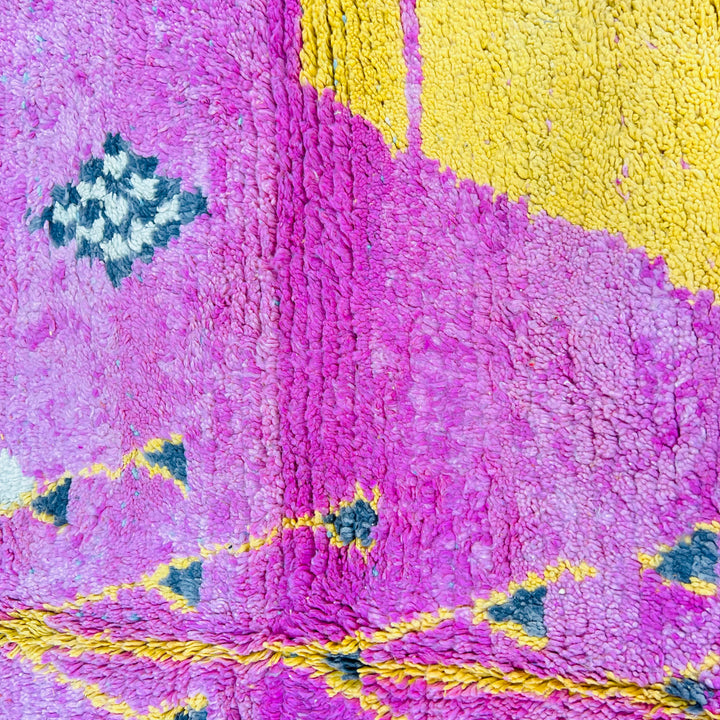 Vintage Moroccan rug in pink, yellow, blue, and cream with triangular and diamond patterns, handmade by Berber women in the Atlas Mountains.