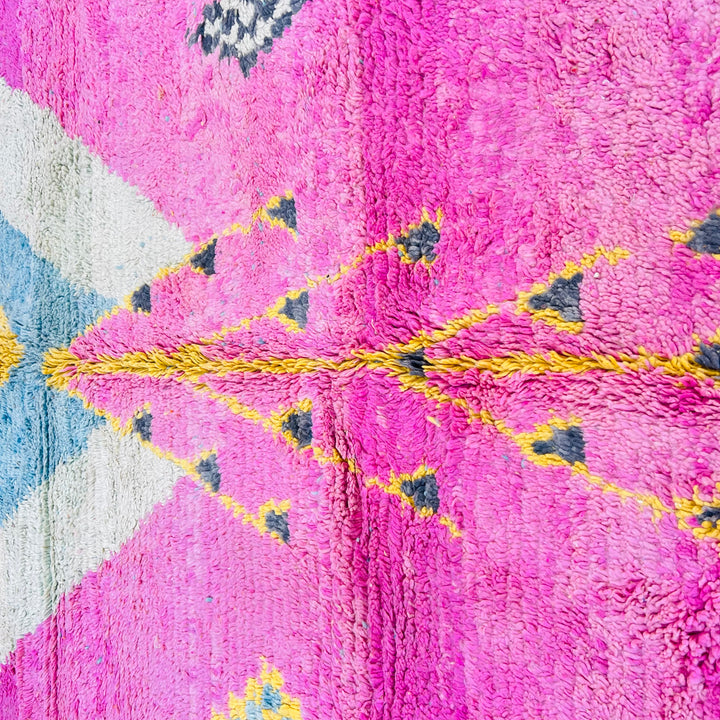 Vintage Moroccan rug with pink, yellow, and blue geometric patterns, 100% wool, handwoven in the Atlas Mountains; stunning artistry.