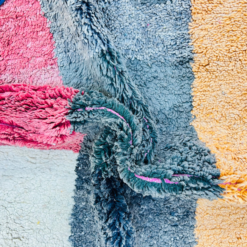 Close-up of vintage Moroccan rug with color block design in pink, grey, and orange. Handmade by Berber artisans. 100% wool.