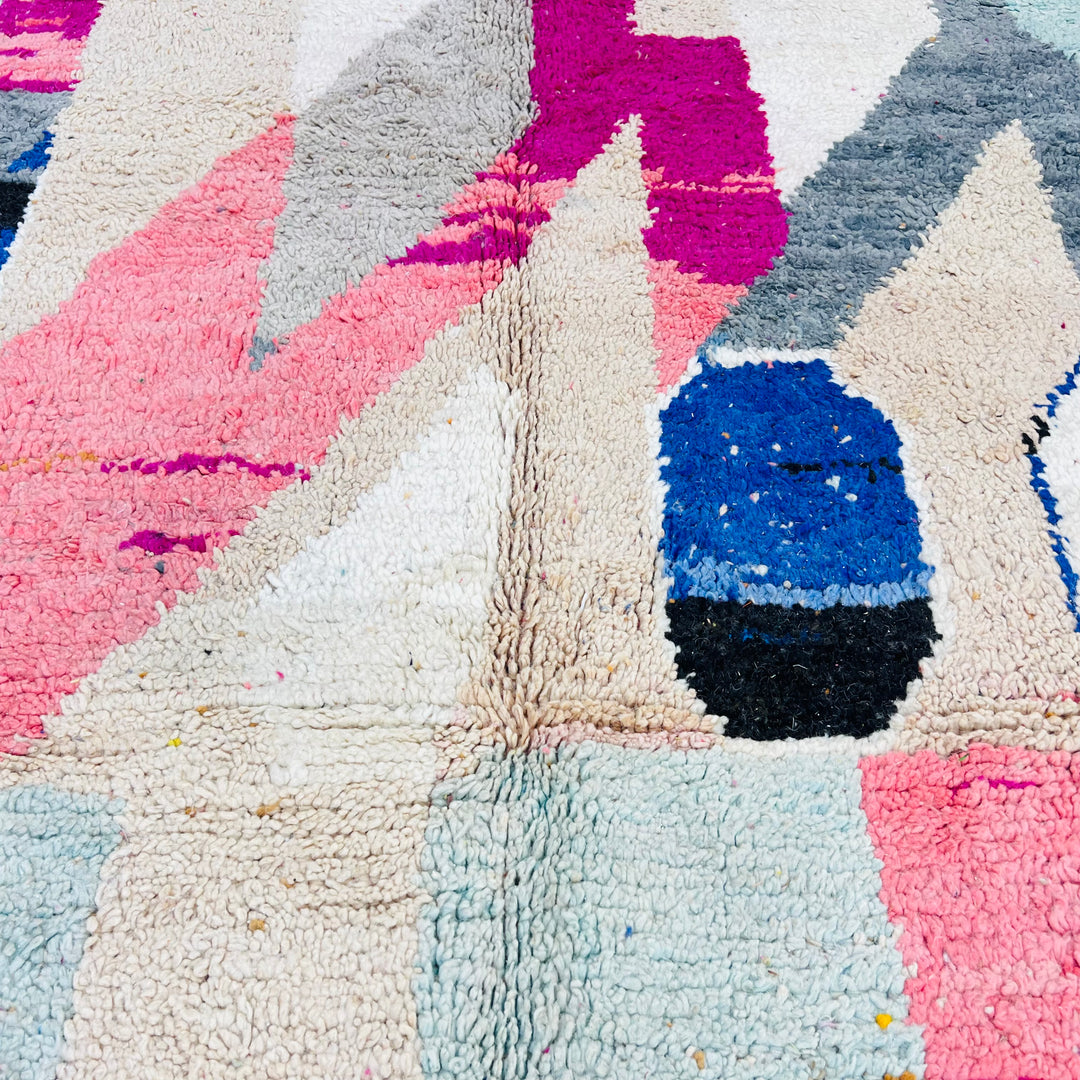 Vintage Moroccan rug with abstract geometric shapes in pink, beige, navy, grey, and mustard; vibrant wool texture.