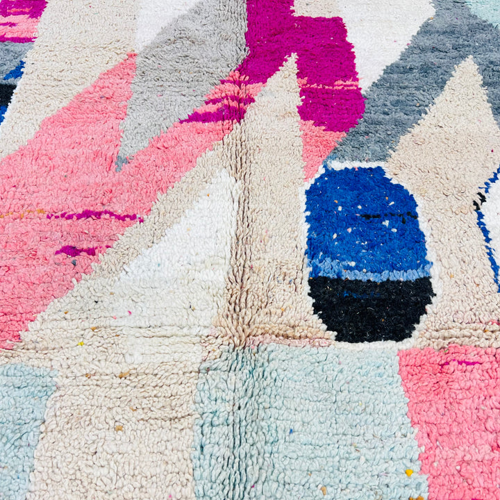 Vintage Moroccan rug with abstract geometric shapes in pink, beige, navy, grey, and mustard; vibrant wool texture.