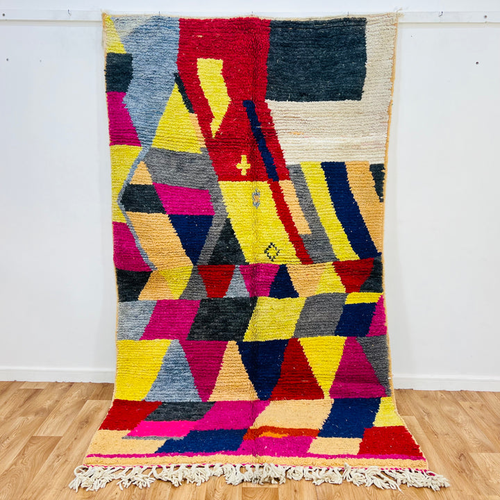 Vintage colorful Moroccan rug with geometric shapes in pink, yellow, navy, and orange. Handwoven wool, 255 x 150 cm. Moroccan Berber design.