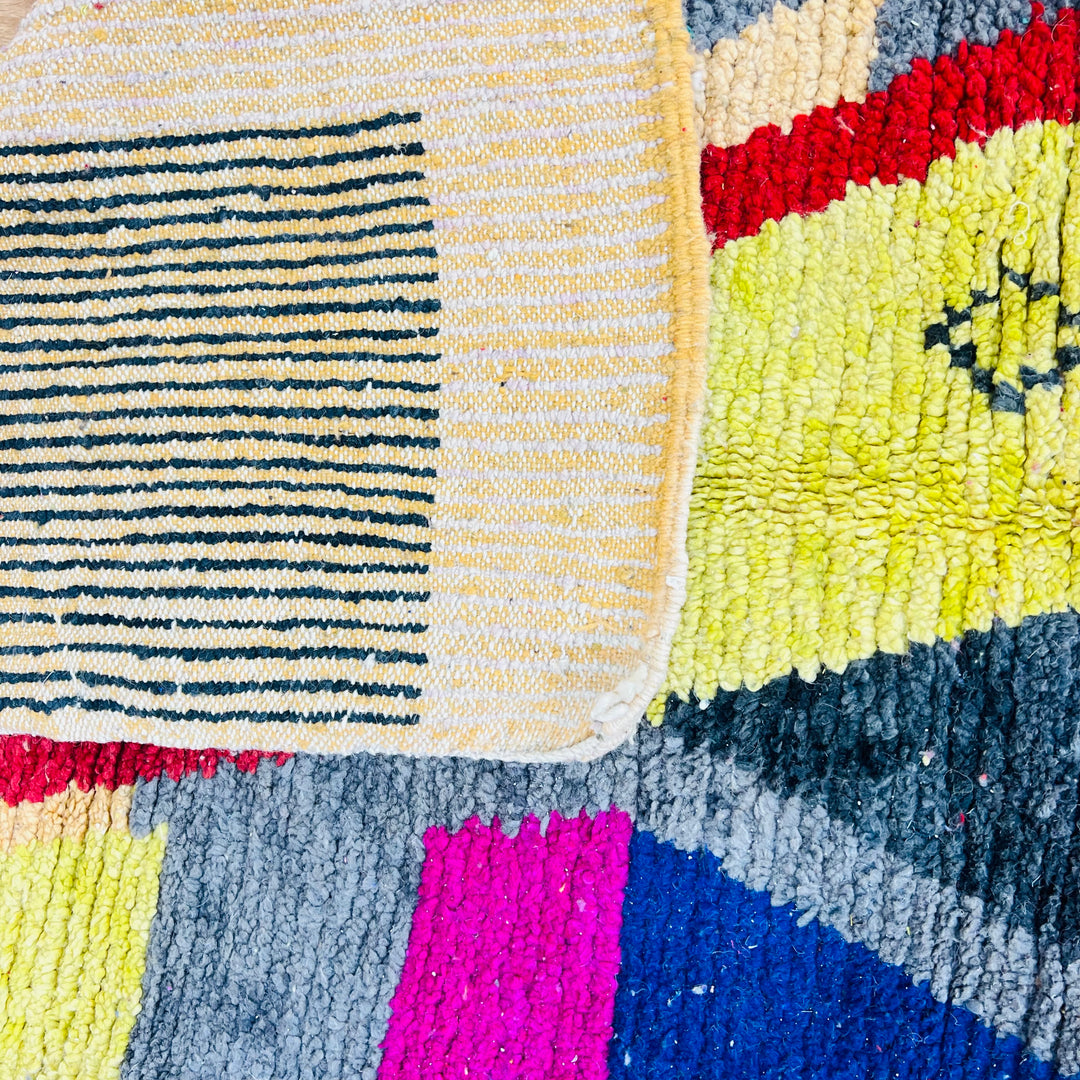 Colorful vintage Moroccan rug with geometric patterns in pink, yellow, navy, grey, red, and orange, handwoven wool.