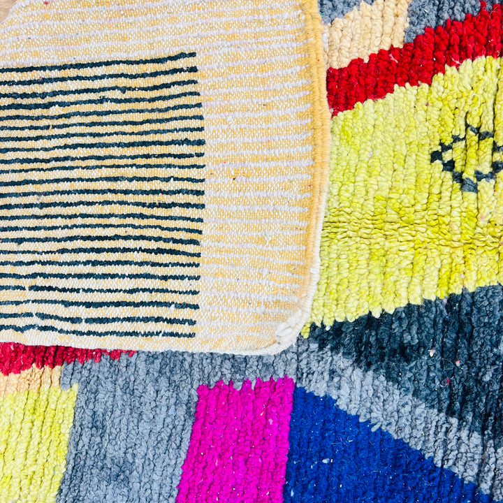 Colorful vintage Moroccan rug with geometric patterns in pink, yellow, navy, grey, red, and orange, handwoven wool.