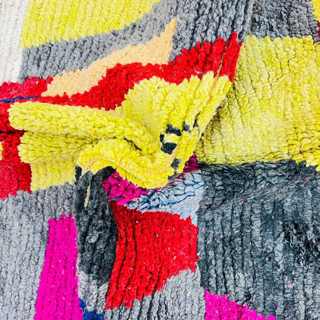 Vintage colorful Moroccan Berber rug with geometric patterns in pink, yellow, navy, grey and red, made of handwoven wool.
