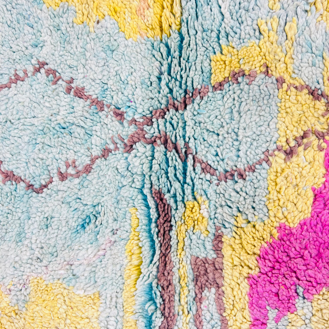 Close-up of a vintage Moroccan rug with pastel colors, handwoven diamond motifs, and vibrant hues for authentic Berber style.