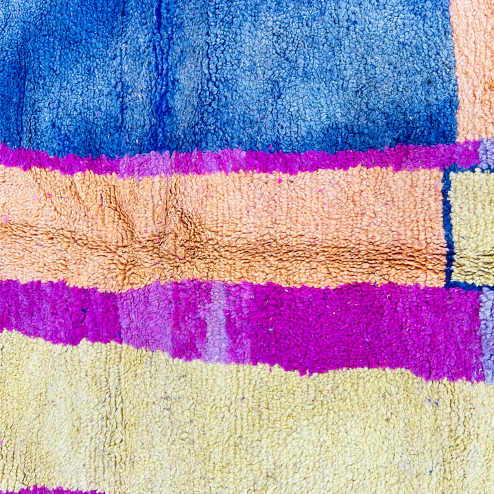 Vintage Moroccan rug with vibrant bands of magenta, navy, and pastel colors, showcasing Berber artistry.