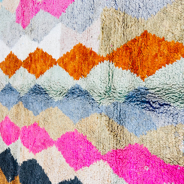 Vintage Moroccan wool rug with colorful diamond pattern, featuring pink, terracotta, and turquoise hues. Hand-knotted by Berber artisans.