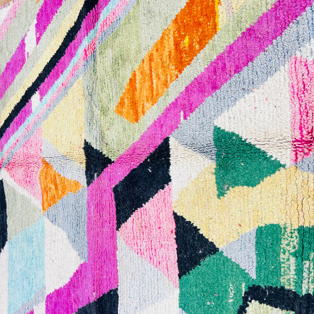 Vintage Moroccan rug with geometric patterns and vibrant colors, including green, pink, orange, and black. Handwoven by Berber artisans.