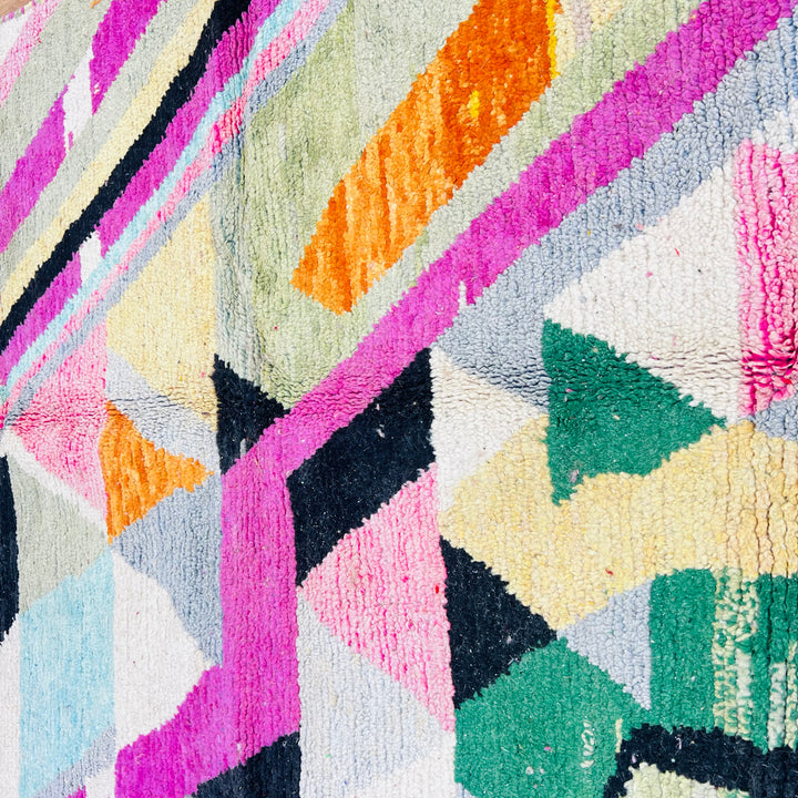 Vintage Moroccan rug with geometric patterns and vibrant colors, including green, pink, orange, and black. Handwoven by Berber artisans.