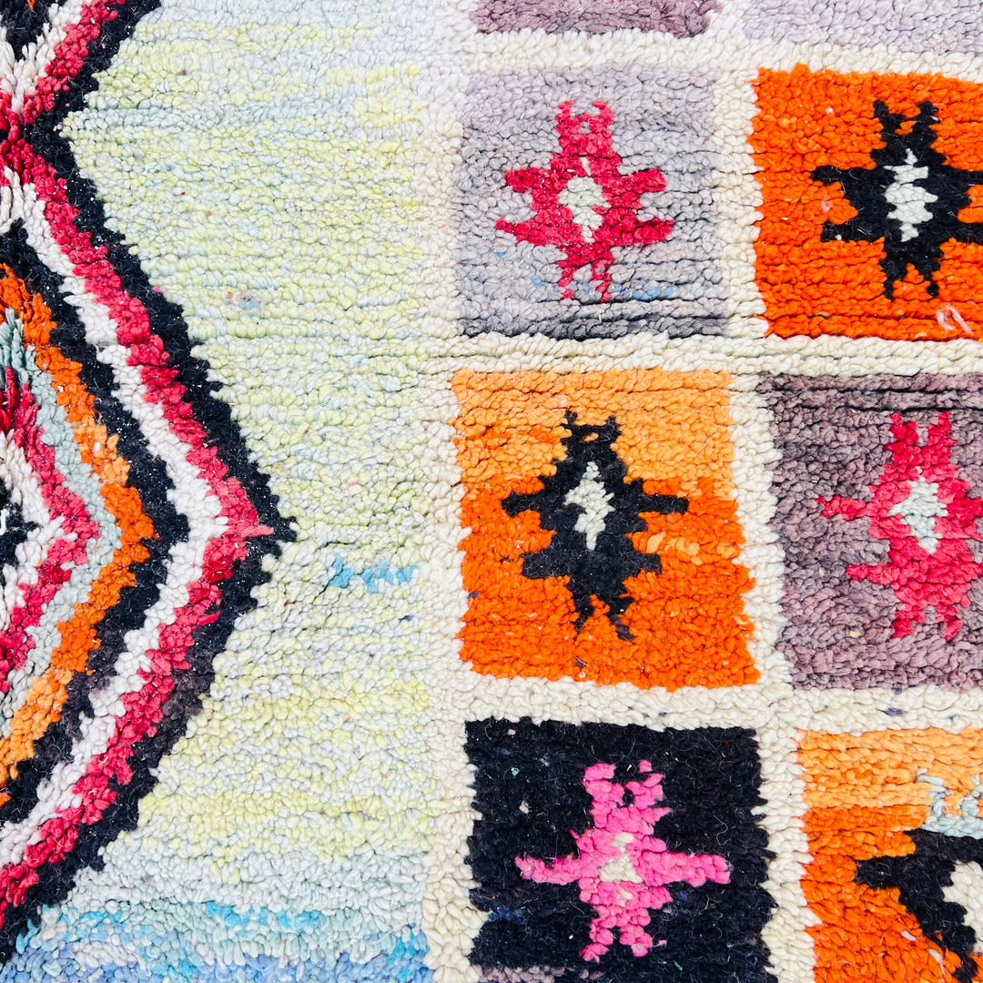 Handmade vintage Moroccan rug with vibrant diamond and star motifs in orange, red, black, and cream, crafted by Berber artisans.