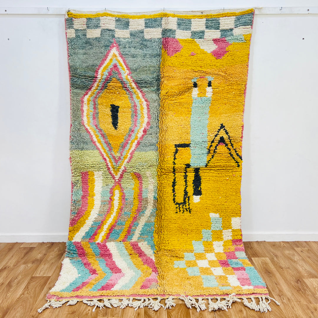 Vintage Moroccan rug with yellow field, abstract Berber symbols, geometric diamond medallion, and rainbow zigzags.
