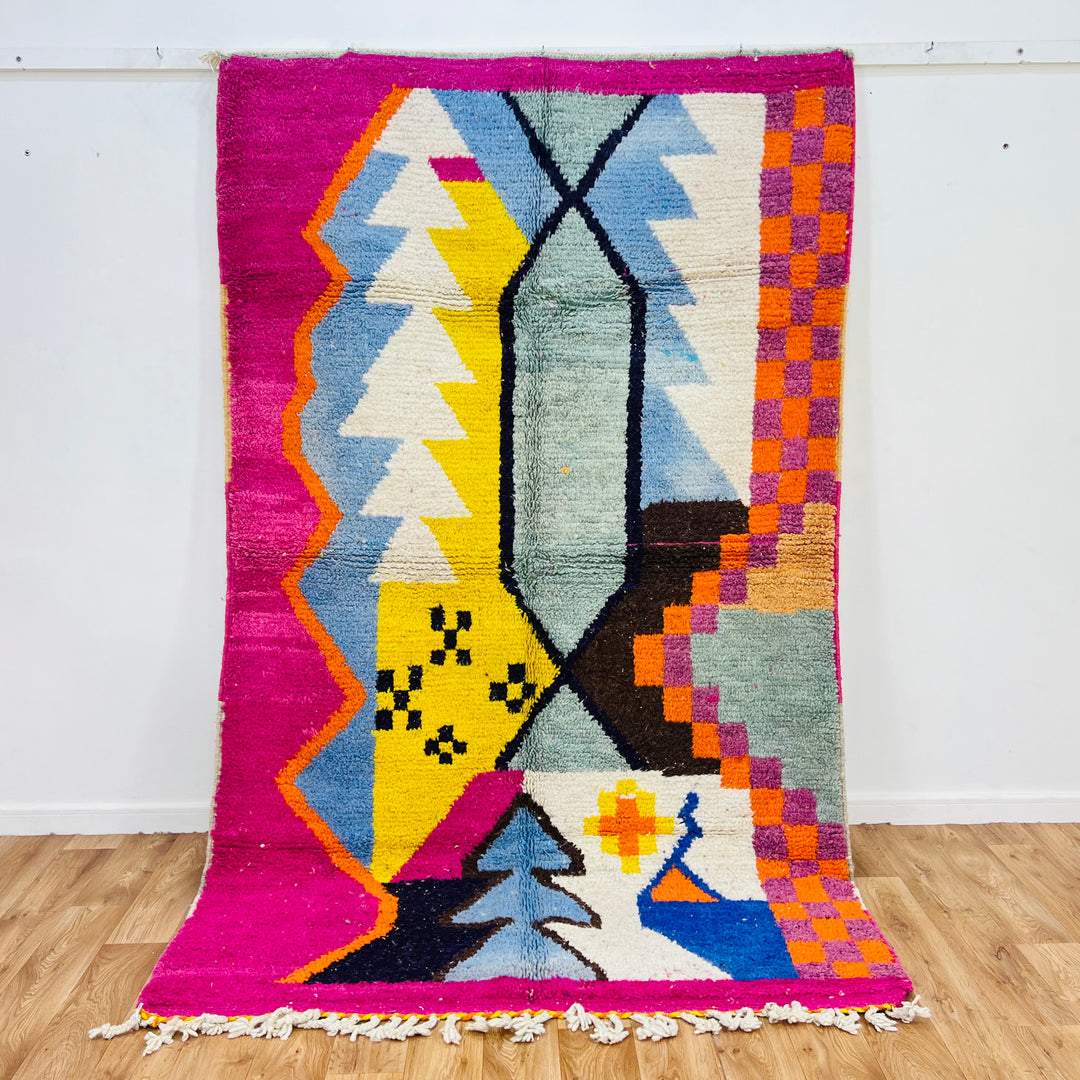 Colorful abstract vintage Moroccan rug with geometric motifs, magenta, yellow, blue, and black hues, handmade Berber symbolism.