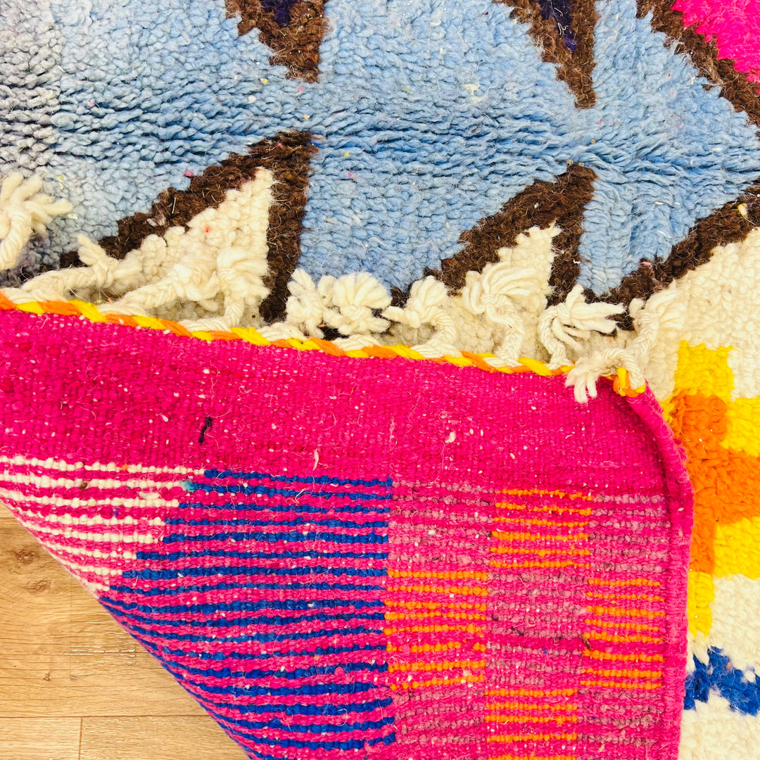 Colorful abstract vintage Moroccan rug with geometric patterns in pink, blue, orange, featuring Berber symbolism and wool texture.