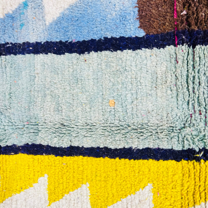 Colorful abstract vintage Moroccan rug with geometric patterns in blue, yellow, and brown wool, highlighting Berber symbolism.