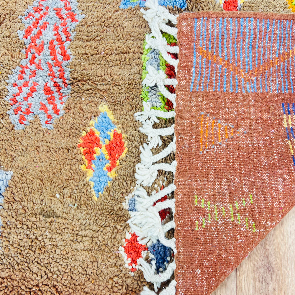 Close-up of handmade vintage Moroccan rug with Berber symbols in earthy tones, showcasing detailed weaving and vibrant colors.