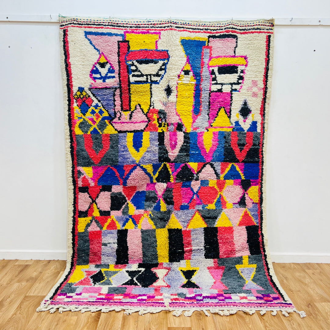 Vintage Moroccan rug with pink, yellow, blue geometric patterns, hand-knotted, Berber artistry, 8.6 x 4.9 ft, vibrant colors.