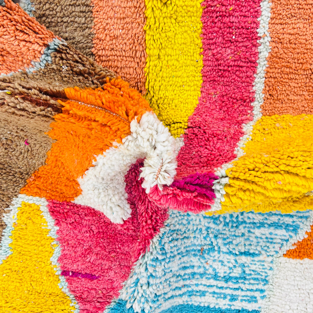 Colorful abstract Moroccan wool rug with geometric patterns, featuring magenta, turquoise, yellow, and orange for vibrant decor.