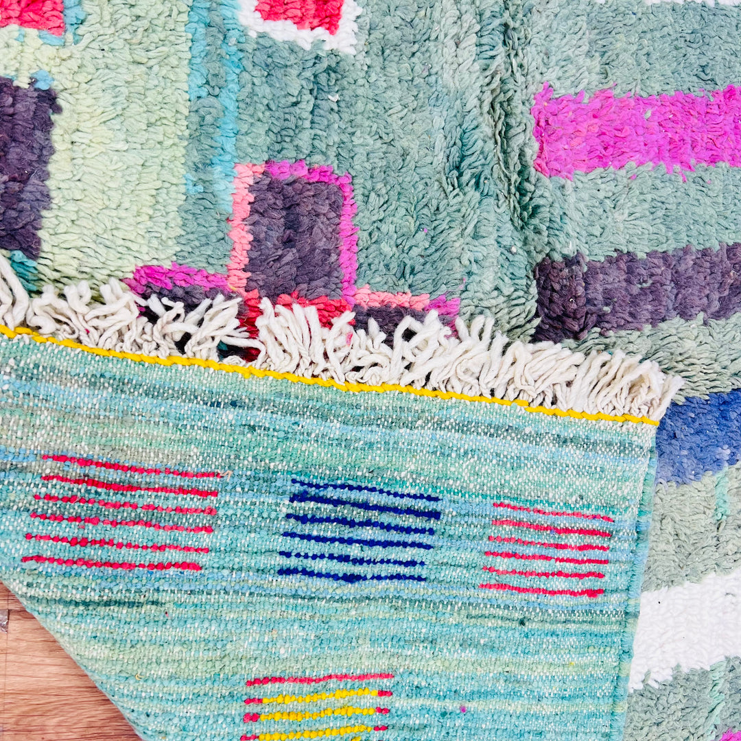 Vintage Moroccan rug with colorful geometric patterns in turquoise, red, yellow, and violet. Traditional Berber design.
