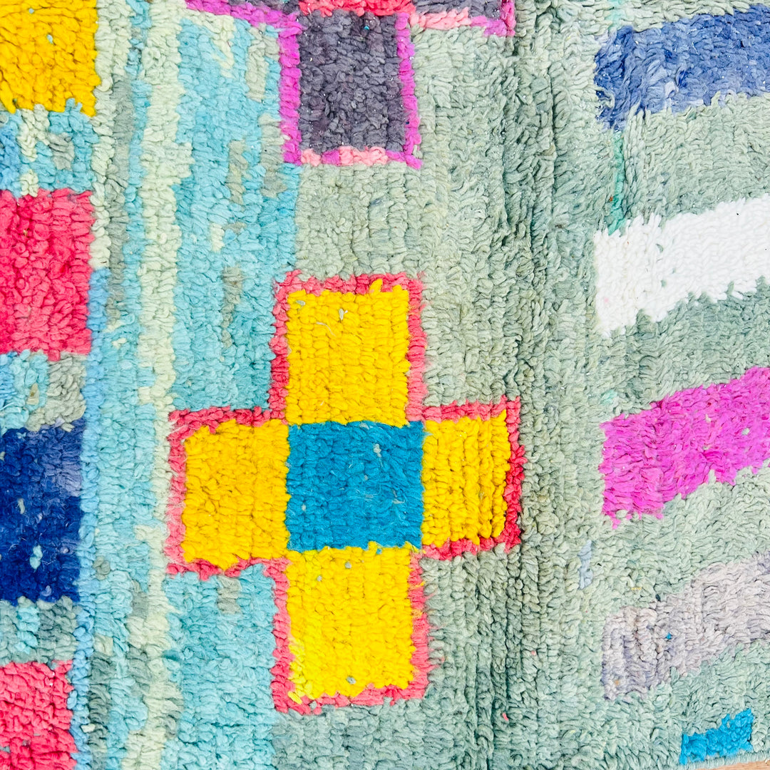 Colorful geometric patterns on vintage Moroccan rug, featuring yellow and blue crosses with vibrant tones. Ideal for modern interiors.