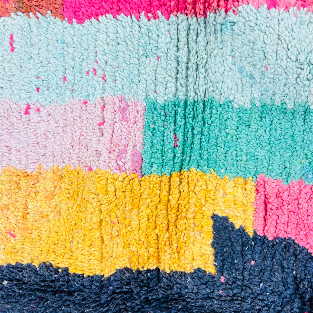 Vintage Moroccan rug with bold stripes in orange, pink, turquoise, and yellow, featuring a black abstract pattern. Handmade wool rug.