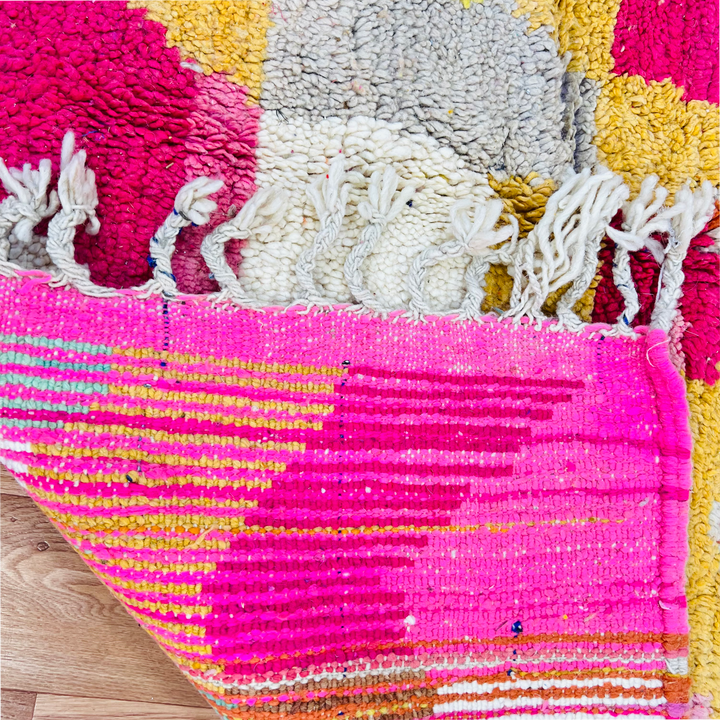 Colorful vintage Moroccan Berber rug with pink, yellow, and white patterns, showcasing traditional handwoven craftsmanship and fringes.