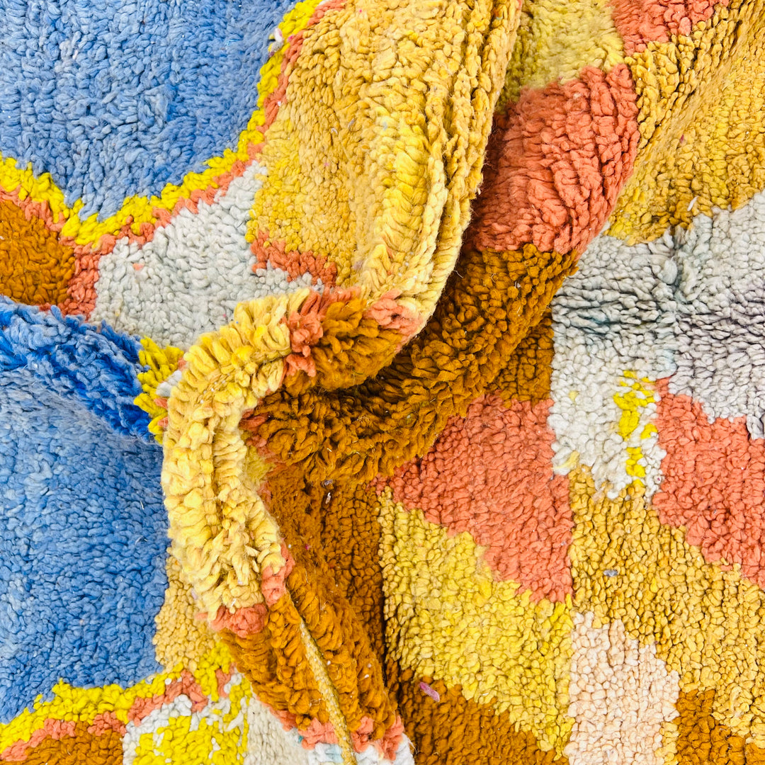 Close-up of a colorful vintage Moroccan Berber wool rug with blue, yellow, and red diamond patterns.