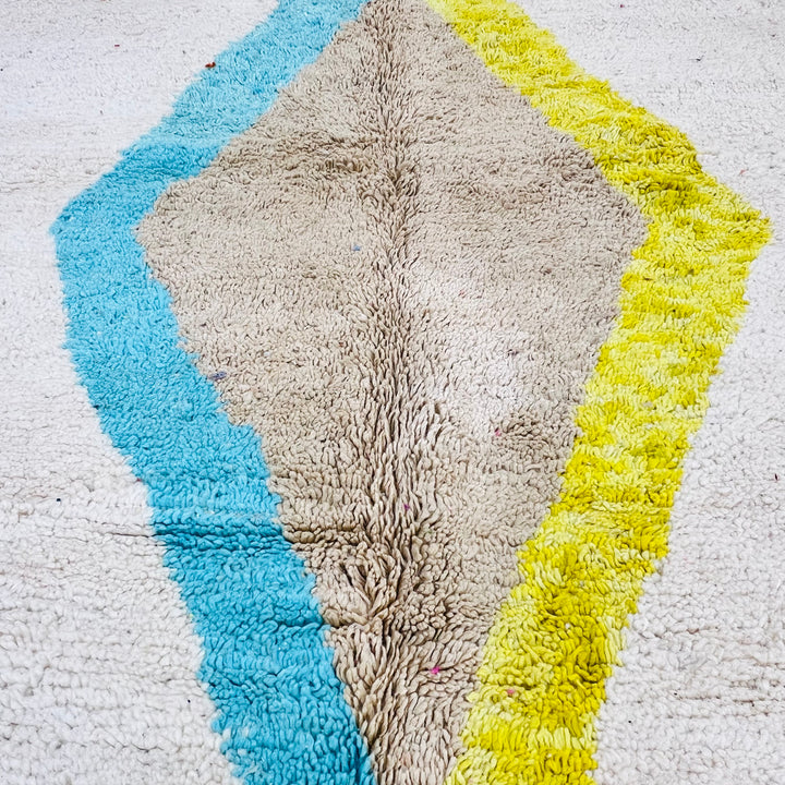 Minimalist vintage Moroccan Berber rug with blue, brown, and yellow diamond pattern on ivory wool background. 8x5 ft.