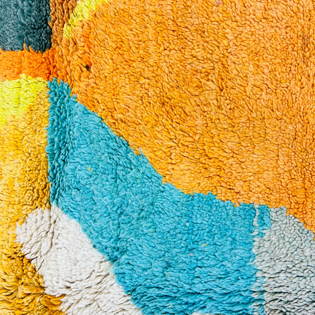 Vintage Moroccan rug with vibrant abstract design in turquoise, mustard, and orange showcasing traditional Berber craftsmanship.