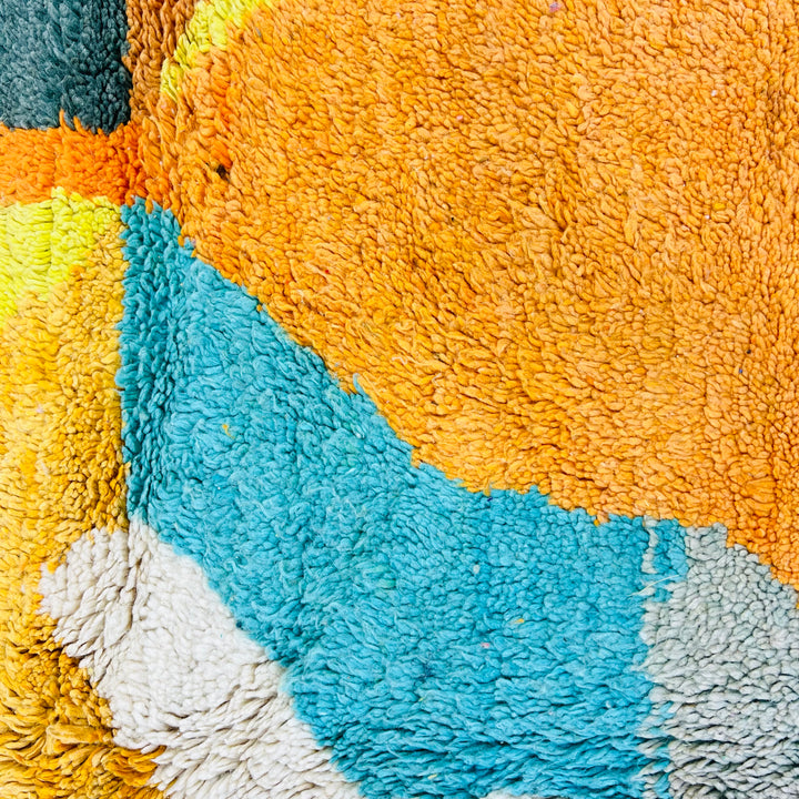 Vintage Moroccan rug with vibrant abstract design in turquoise, mustard, and orange showcasing traditional Berber craftsmanship.
