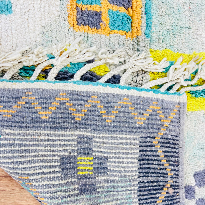 Close-up of Chevron Vintage Moroccan Rug featuring zigzag patterns in yellow, turquoise, and grey. Handwoven Berber wool craftsmanship.
