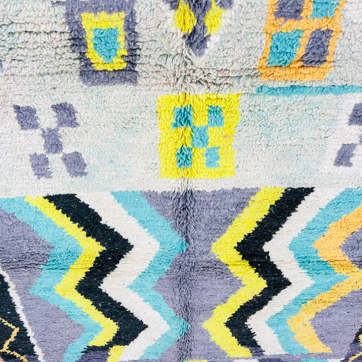 Vintage Moroccan rug with chevron patterns in yellow, turquoise, and black. Handcrafted Berber wool rug featuring symbolic motifs.