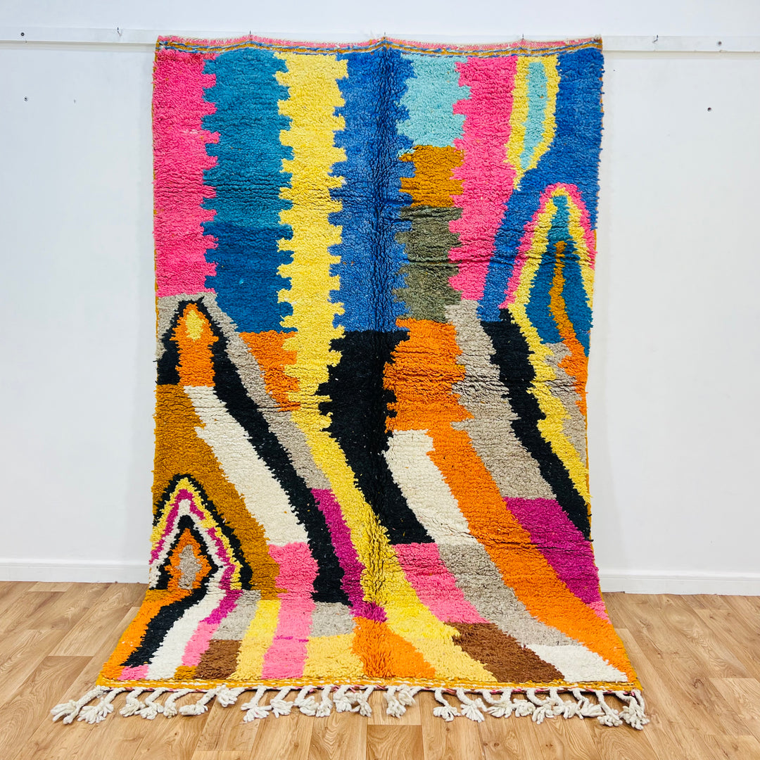 Colorful vintage Moroccan wool rug with abstract lines, featuring pink, orange, yellow, blue, and black, handcrafted in the Atlas Mountains.