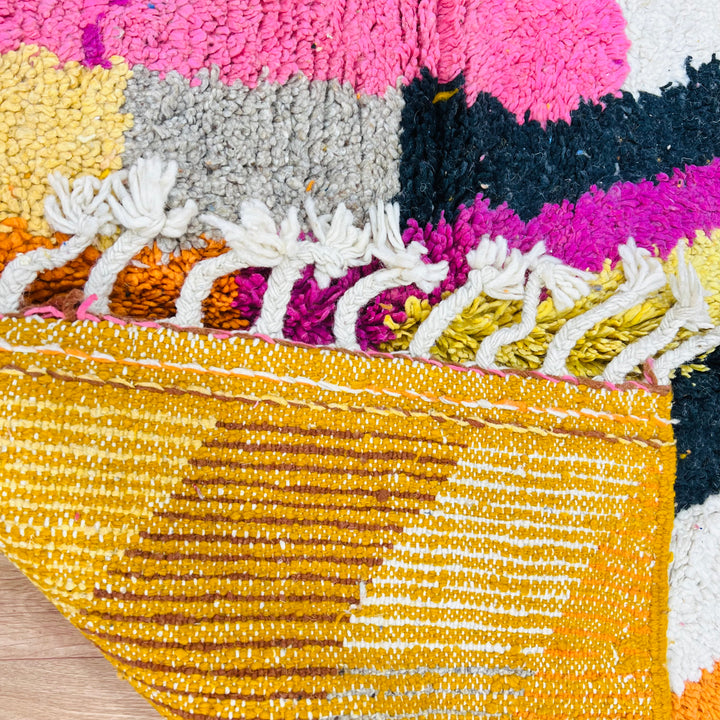Colorful vintage Moroccan rug with bold abstract lines and color blocking in pink, orange, yellow, blue, and black.