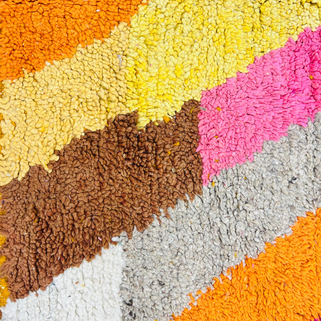 Abstract colorful design of a vintage Moroccan rug with textured pink, orange, yellow, and brown wool handcrafted detail.