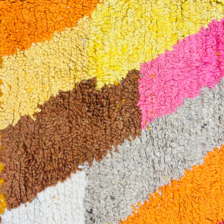 Abstract colorful design of a vintage Moroccan rug with textured pink, orange, yellow, and brown wool handcrafted detail.