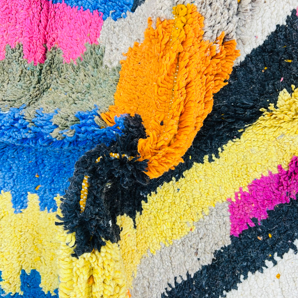 Colorful vintage Moroccan rug with abstract patterns in pink, orange, yellow, blue, and black shades, showcasing Berber craftsmanship.