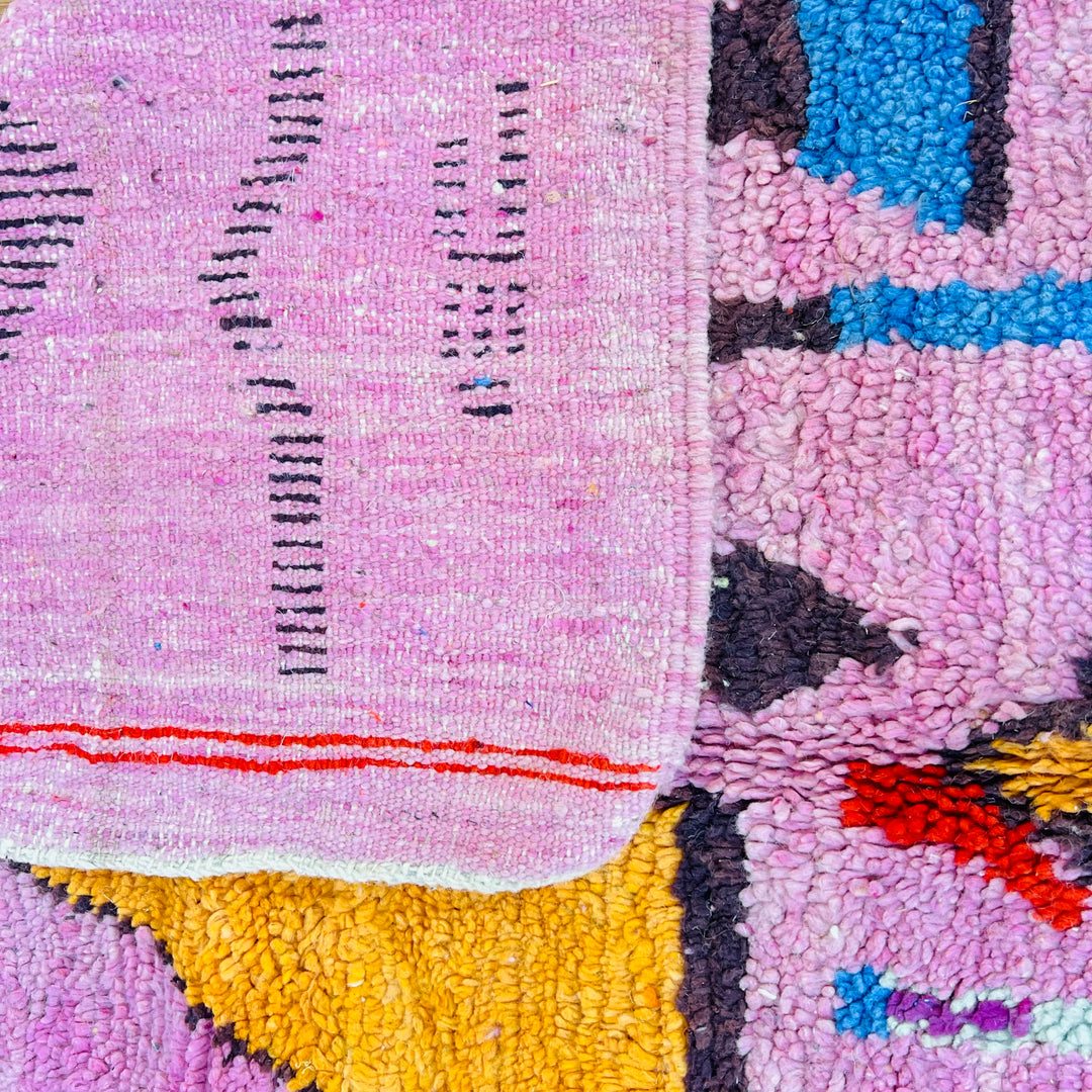 Pink vintage Moroccan rug with Berber motifs in red, orange, blue, and yellow, showcasing traditional Moroccan craftsmanship.