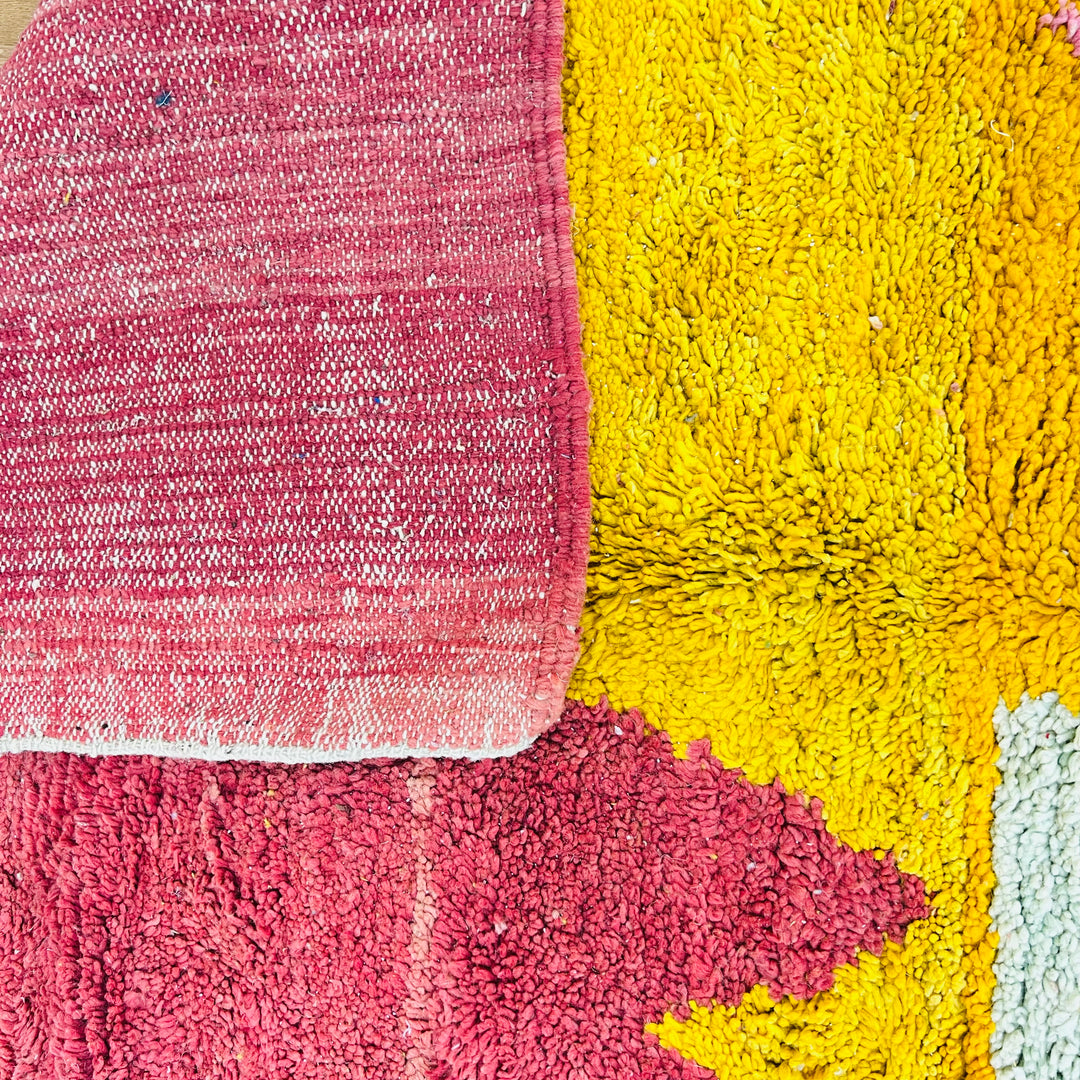 Bold abstract Moroccan rug with vivid crimson, yellow, and pink geometric patterns, handmade by Berber artisans.